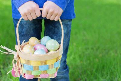 Child holding easter basket full of eggs